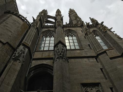 Directly above, we see some of the architecture of the abbey.  Arched windows are perhaps 20′ above, with intricately carved pillars supporting buttresses.  Gargoyles lean out, and the peaks of various spires have spines that make them resemble odd hedgehogs from below.